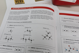 Das Bild zeigt eine Seite aus einem Lehrbuch über Molekülbaukästen, die Beispiele für chemische Verbindungen wie Alkane und Alkene präsentieren. Es werden verschiedene Molekülstrukturen und deren allgemeine Formeln dargestellt, um den Einsatz von Molekülmodellen im Unterricht zu verdeutlichen.