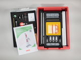 Das Bild zeigt ein Experimentierset für Schüler im Bereich Mechanik, das in einem roten Kasten organisiert ist. Es enthält verschiedene physikalische Werkzeuge und ein Handbuch mit der Bezeichnung "Mechanik 2.0" für Lehrzwecke.