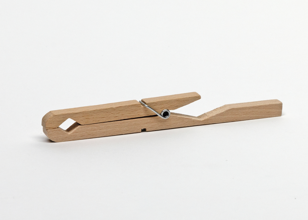 Das Bild zeigt eine Holz-Wäscheklammer, die aus einem hellen, naturbelassenen Holz gefertigt ist. Die Klammer verfügt über eine Metallfeder und ist einfach konstruiert, ideal für verschiedene experimentelle Anwendungen im Bildungsbereich.