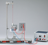 Das Bild zeigt ein physikalisches Experimentiergerät zur Untersuchung von elektromagnetischen Phänomenen. Es besteht aus einem Aufbau mit einer Drahtspule, einer Stromversorgung und ist auf einem stabilen Gestell montiert.