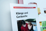Das Bild zeigt eine Lehrerhandreichung mit dem Titel „Klänge und Geräusche“. Es handelt sich um Materialien für Experimente, die im deutschen Bildungswesen eingesetzt werden, um das Verständnis von Klängen und Geräuschen zu fördern.