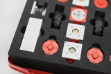 Das Bild zeigt ein Set aus mehreren experimentellen Bauteilen, die in einem gepolsterten Behälter angeordnet sind. Es sind rote und weiße Elemente, darunter Räder und Steckverbindungen, die für verschiedene technische Experimente im Bildungswesen verwendet werden können.