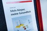 Ein Schüler-Set für Experimente zu Körper und Gesundheit wird gezeigt. Es umfasst verschiedene Reagenzgläser und Proben, die zur Durchführung von Experimenten im Bildungsbereich verwendet werden.
