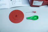 Vorliegend sind verschiedene Materialien für ein Experimentier-Set zum Thema Luft. Zu sehen sind ein roter Kunststoffdeckel, ein grüner Ballon und eine transparente Verbindung, die vermutlich zur Durchführung von Experimenten genutzt werden.