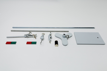 Ein Set aus physikalischen Experimentierutensilien liegt auf weißem Grund. Es umfasst Metallstangen, Klemmen, Magnete sowie eine graue Basisplatte.