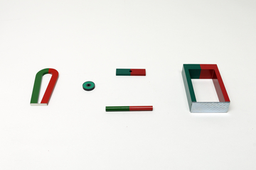 Verschiedene Magnete in Form von Hufeisen, Stäben und einem Rahmen liegen auf weißem Grund. Die Objekte sind farblich in Grün und Rot markiert, um die Pole zu kennzeichnen.