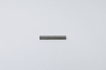 Ein kleiner, zylindrischer Metallstab liegt horizontal auf einem hellgrauen Untergrund. Er weist eine glatte, reflektierende Oberfläche auf.