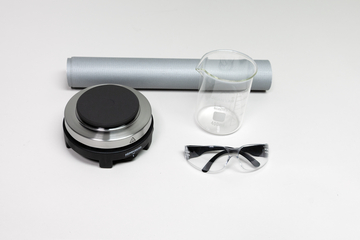 Mehrere transparente, zylindrische Glas- oder Kunststoffobjekte liegen auf einem weißen Hintergrund. Die Gegenstände weisen verschiedene Krümmungen und Lichtreflexionen auf, die auf optische Experimente hindeuten.