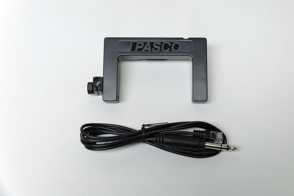 Ein schwarzes PASCO-Messgerät in U-Form liegt auf einem weißen Hintergrund. Darunter befindet sich ein zusammengerolltes schwarzes Verbindungskabel.