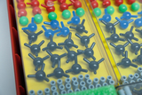 Bunte Kunststoff-Kugeln mit Verbindungsstiften liegen sortiert in einer gelben Kunststoffbox. Dieses Molekülmodell dient zur Visualisierung chemischer Strukturen im Unterricht.