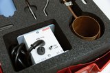 Ein Cornelsen-Experimentierkoffer enthält ein elektrisches Gerät mit Schalter und Kabel sowie diverse metallische Werkzeuge. Die Komponenten sind sicher in einem passgenauen Schaumstoffinlay untergebracht.