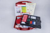 Eine rote Transportbox enthält ein Set für Experimente zum sicheren Umgang mit Feuer. Neben verschiedenen Werkzeugen und Materialien liegen darin eine Anleitung sowie Informationsblätter.