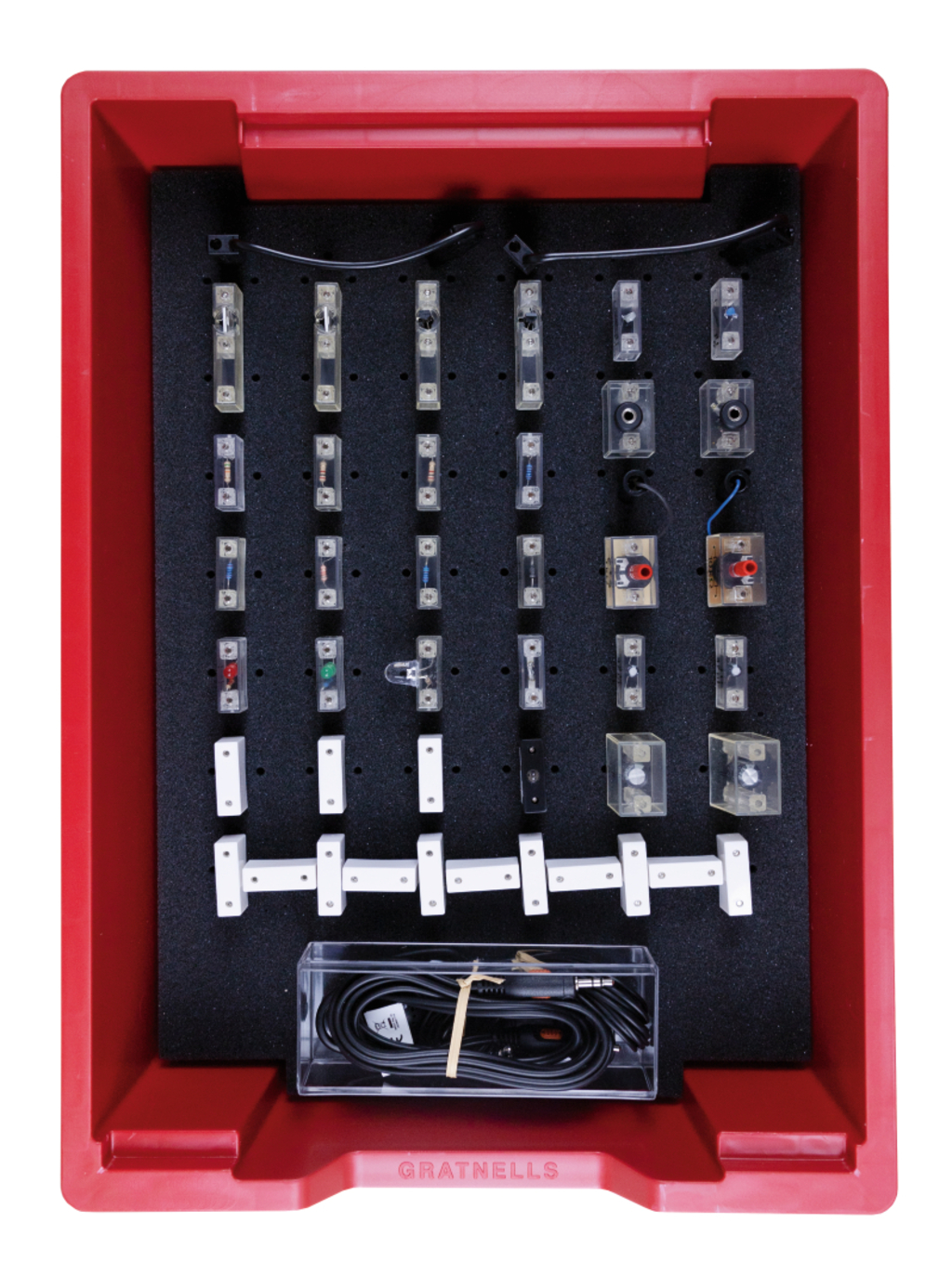 Ein rotes Kunststoffset enthält diverse elektronische Bauteile und Steckmodule, die in schwarzem Schaumstoff fixiert sind. Ergänzt wird das Experimentierkit durch Kabel in einem transparenten Behälter.