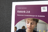 Ein Informationsblatt für den Klassensatz „Elektrik 2.0“ bewirbt Grundschaltungen für Steckplatten von Cornelsen Experimenta. Es zeigt einen konzentrierten Schüler sowie einen QR-Code für zusätzliche Unterstützung.