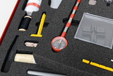 Ein Set aus verschiedenen physikalischen Experimentierutensilien liegt in einer passgenauen Schaumstoffeinlage. Zu sehen sind unter anderem ein Kompass, gelbe Kunststoffteile und ein schwarzes Garn.
