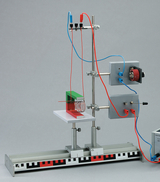 Ein physikalisches Experimentierset zur Demonstration elektromagnetischer Induktion ist auf einem Stativ aufgebaut. Es umfasst eine Spule, eine Stromquelle mit Kabeln und eine Messanordnung auf einer metallischen Basis.
