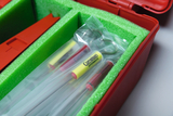 In einem roten Koffer liegen in grünem Schaumstoff mehrere in Plastik verpackte Instrumente der Marke Cornelsen Experimenta. Es handelt sich vermutlich um Laborgeräte für den Bildungsbereich.